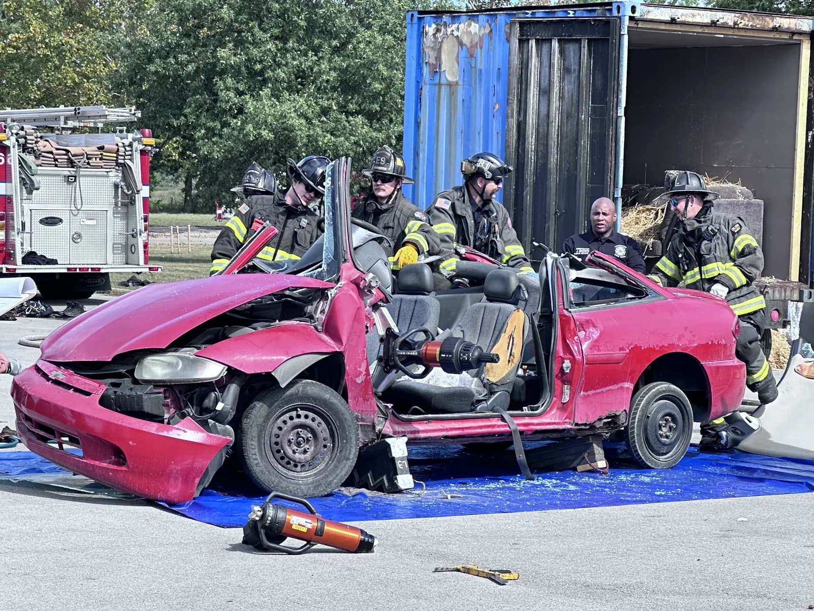Lexington firefighters from Engine 9 and Rescue 1 stand over a red car with its roof cut off during the vehicle extrication demo at the Fire Prevention Festival